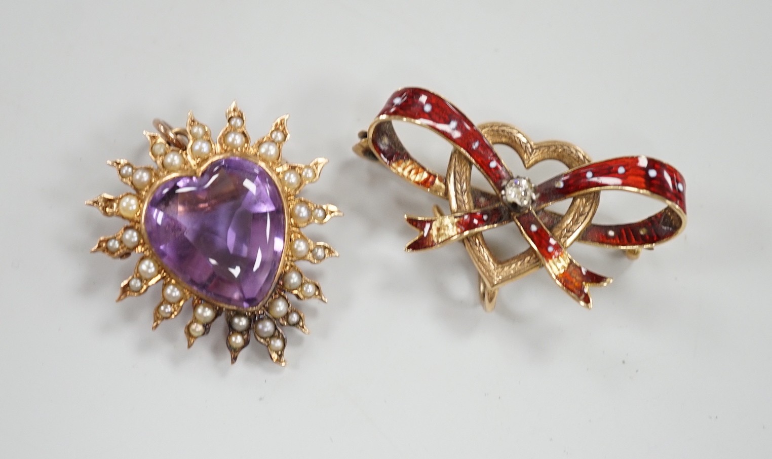 An early 20th century yellow metal amethyst and seed peart set heart shaped pendant brooch, 25mm, gross 5.3 grams and a yellow metal and enamel set ribbon bow and heart brooch (enamel a.f.).